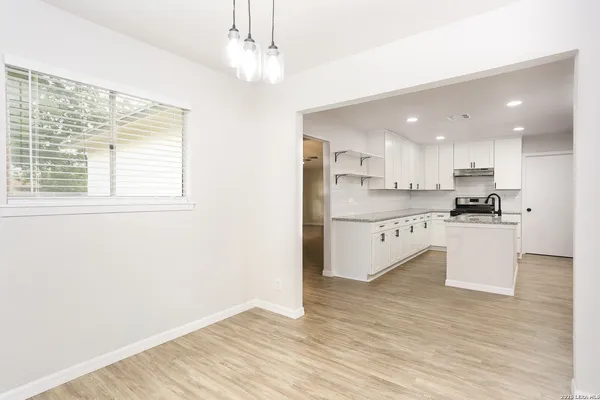 a large white kitchen with stainless steel appliances granite countertop a stove a sink dishwasher and a refrigerator with wooden floor