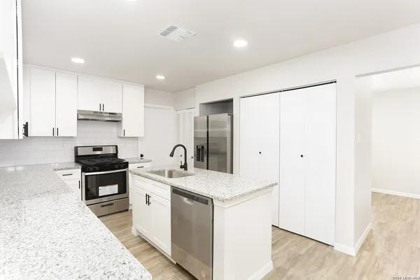 a kitchen with stainless steel appliances granite countertop a sink stove and refrigerator
