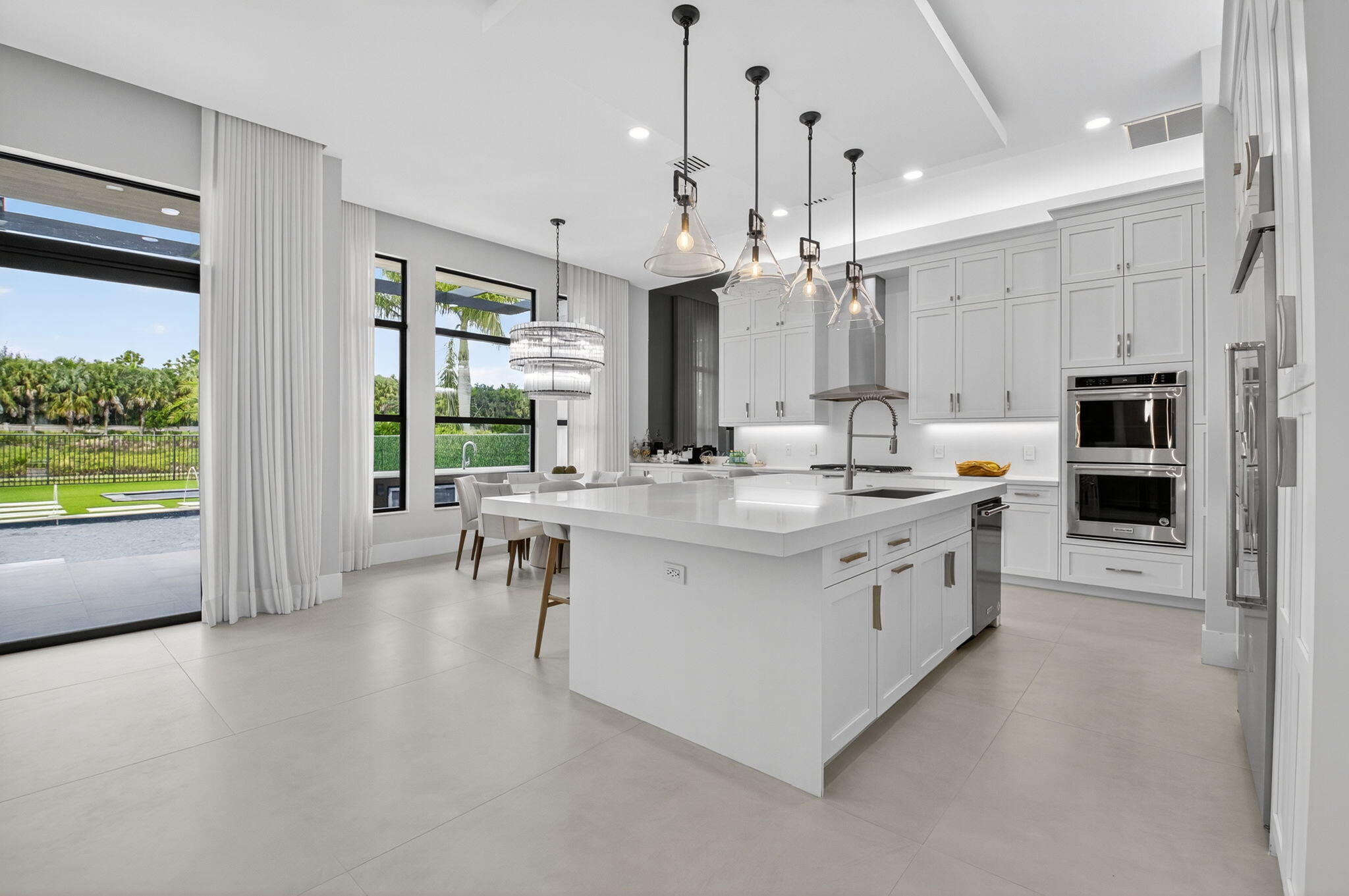 9083 Benedetta Place Boca Raton, FL 33496 - Photo 21 of 112 a large white kitchen with kitchen island a large counter space a sink stainless steel appliances and cabinets