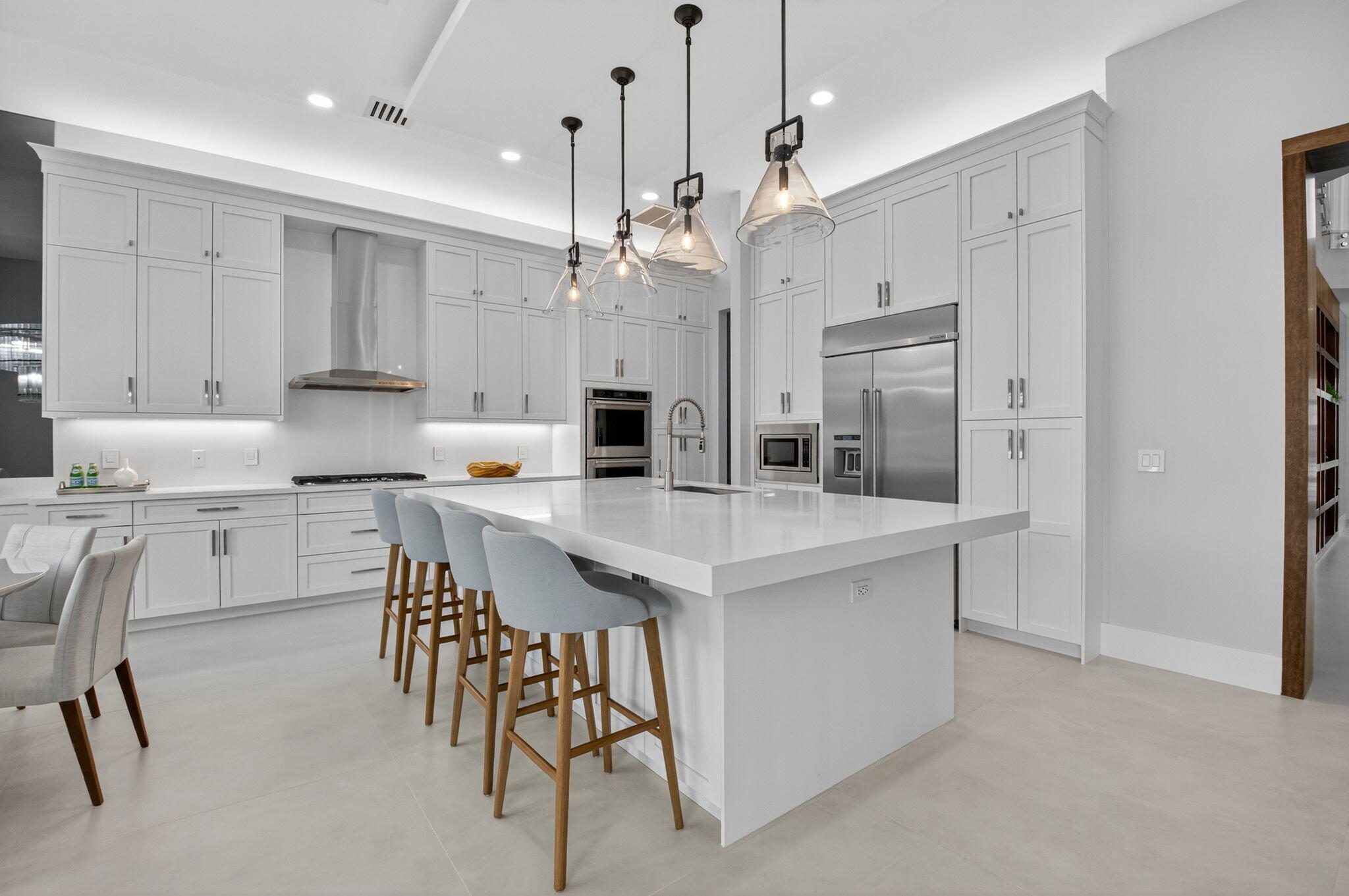 9083 Benedetta Place Boca Raton, FL 33496 - Photo 24 of 112 a kitchen with kitchen island granite countertop a table chairs sink and cabinets