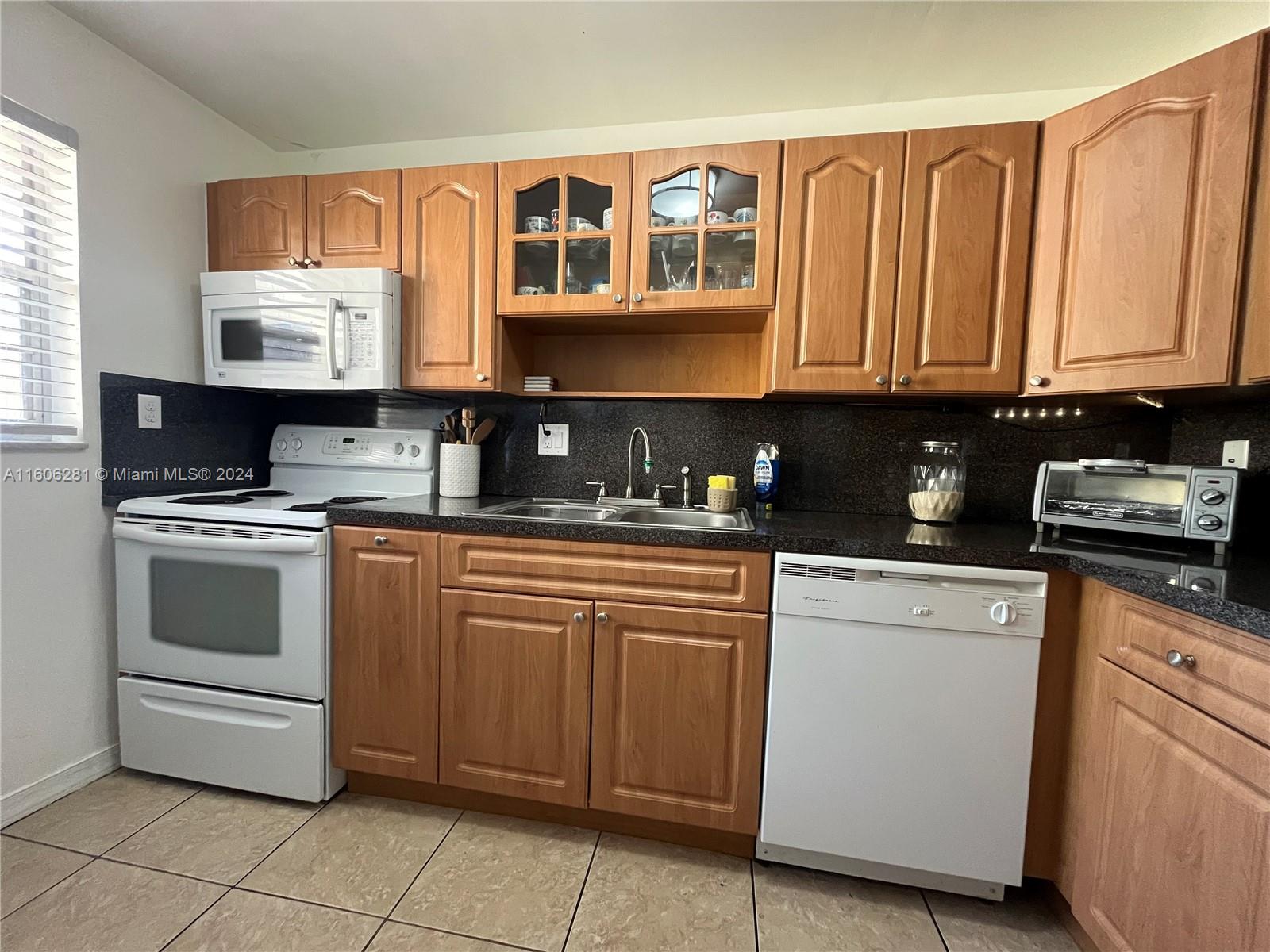 3490 Foxcroft Road, Unit B107 Miramar, FL 33025 - Photo 11 of 32 a kitchen with granite countertop a stove sink and cabinets