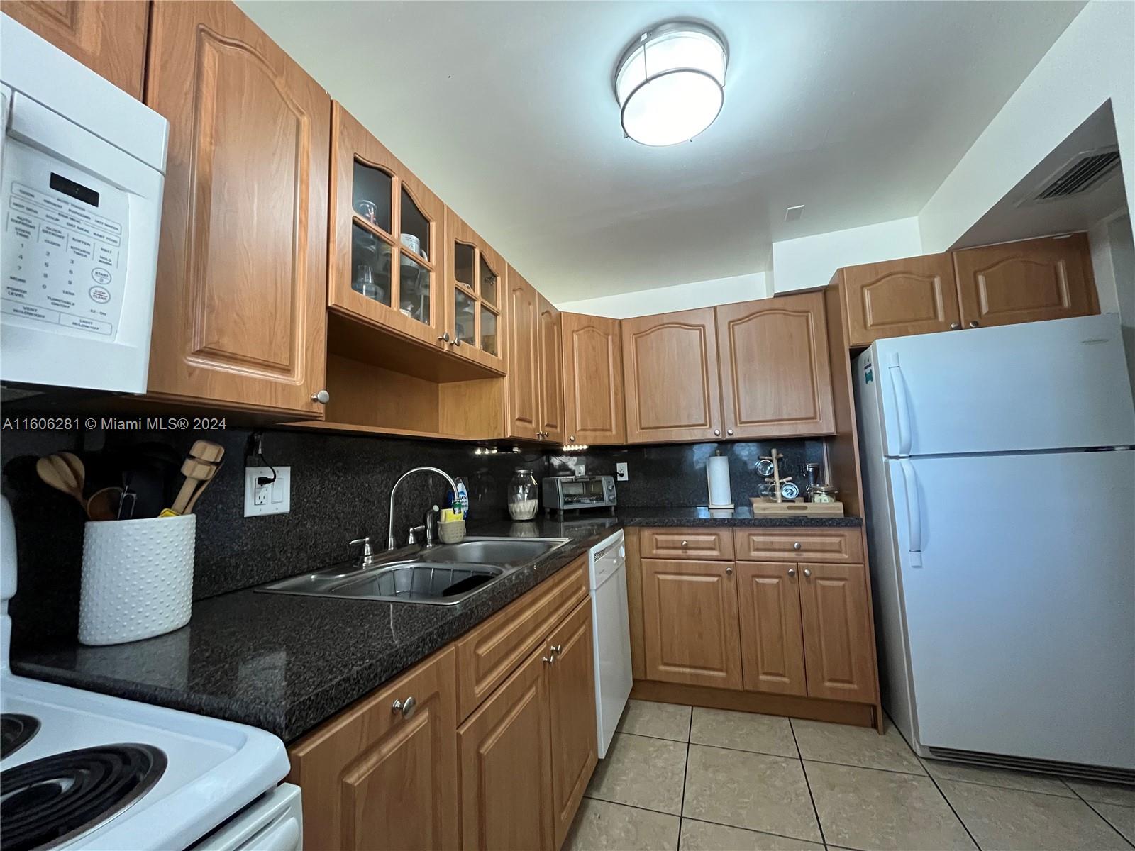 3490 Foxcroft Road, Unit B107 Miramar, FL 33025 - Photo 12 of 32 a kitchen with a sink refrigerator and cabinets