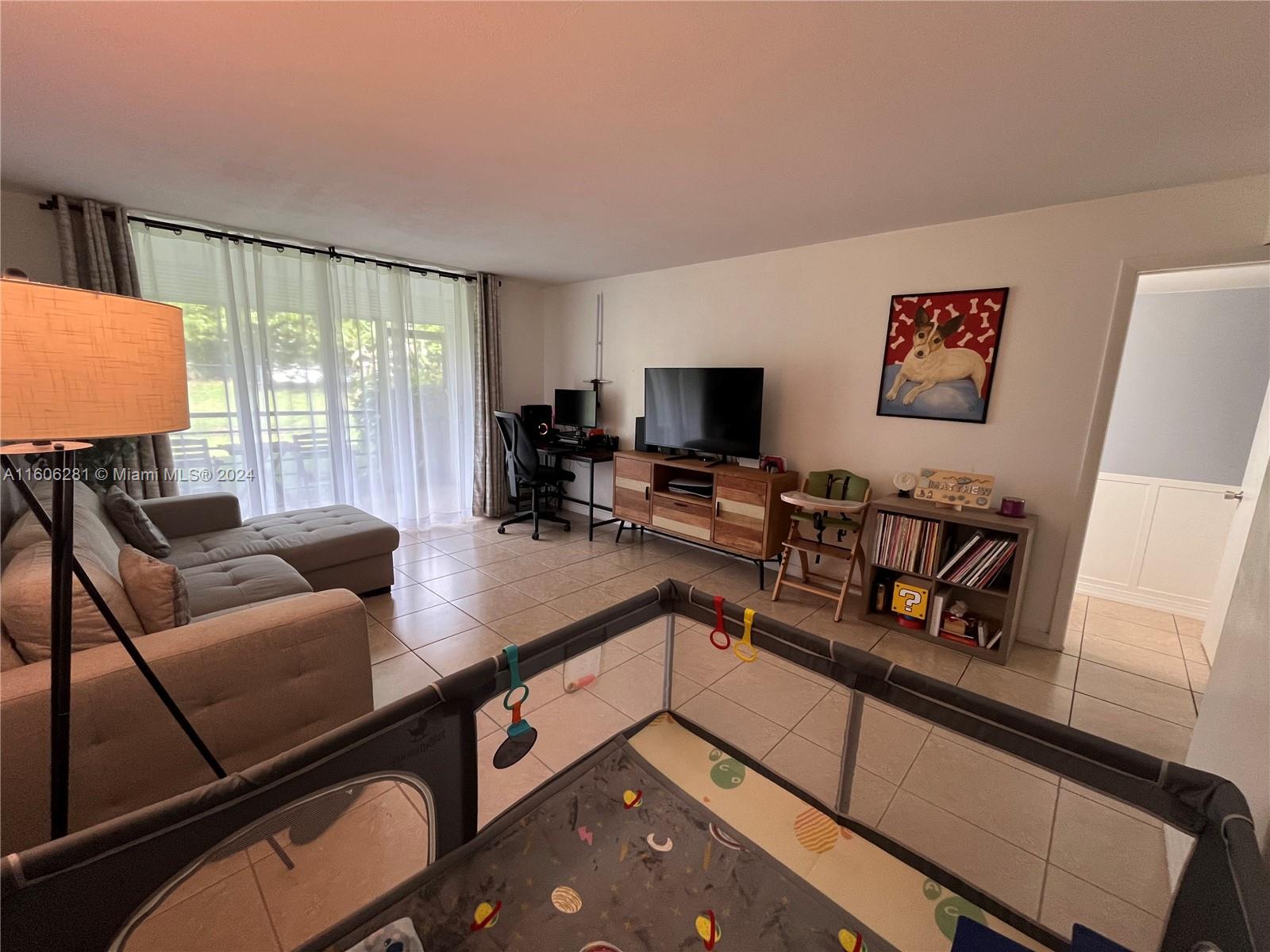 3490 Foxcroft Road, Unit B107 Miramar, FL 33025 - Photo 14 of 32 a living room with furniture and a flat screen tv