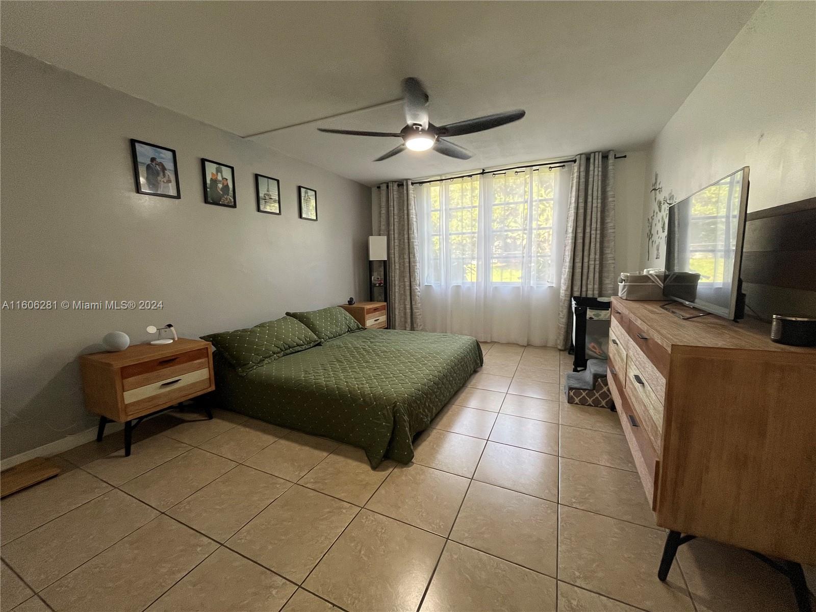 3490 Foxcroft Road, Unit B107 Miramar, FL 33025 - Photo 23 of 32 a spacious bedroom with a bed and a flat screen tv