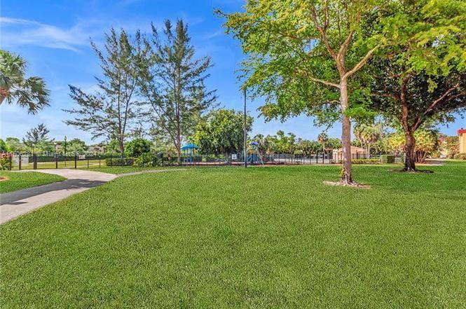 3490 Foxcroft Road, Unit B107 Miramar, FL 33025 - Photo 5 of 32 a view of grassy field with benches and trees all around