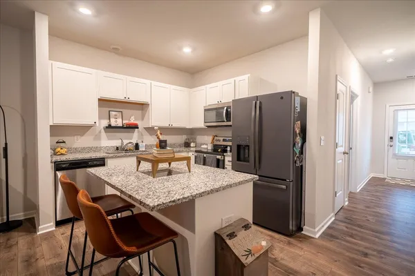 a kitchen with granite countertop a refrigerator a stove a sink and a refrigerator