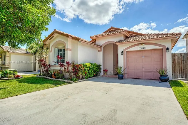 a view of a white house with a small yard and large tree