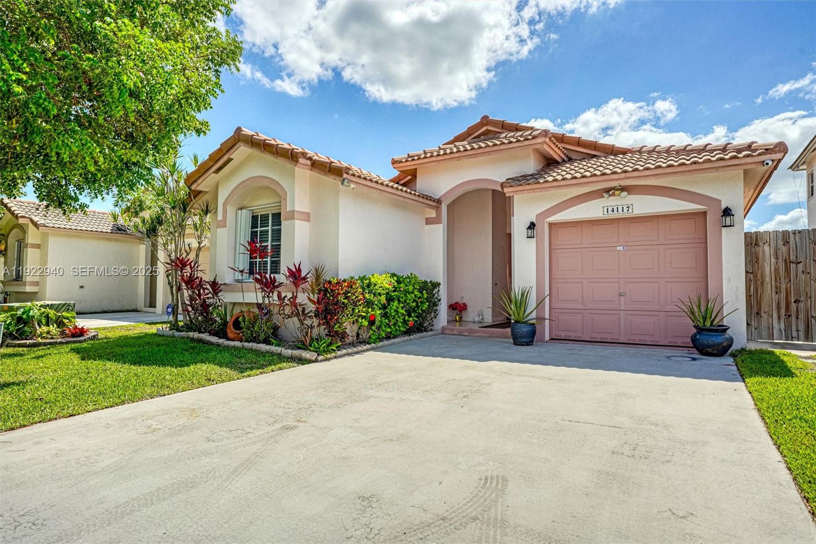 a view of a white house with a small yard and large tree