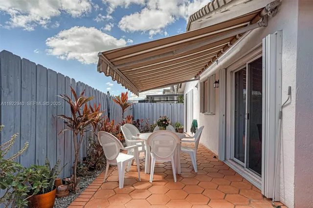 a patio with table and chairs and potted plants