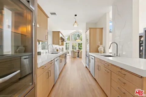 a large kitchen with kitchen island wooden floor a large window and stainless steel appliances