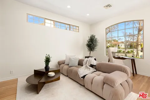 a living room with furniture plant and wall painting