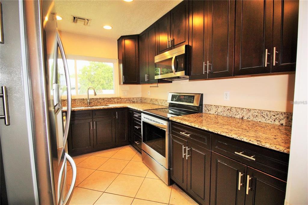 1609 Tulane Street Orlando, FL 32804 - Photo 3 of 21 a kitchen with stainless steel appliances granite countertop wooden cabinets a refrigerator and a sink