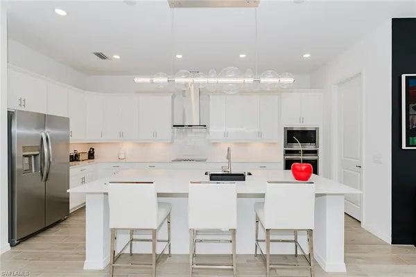 a kitchen with a dining table chairs refrigerator and microwave