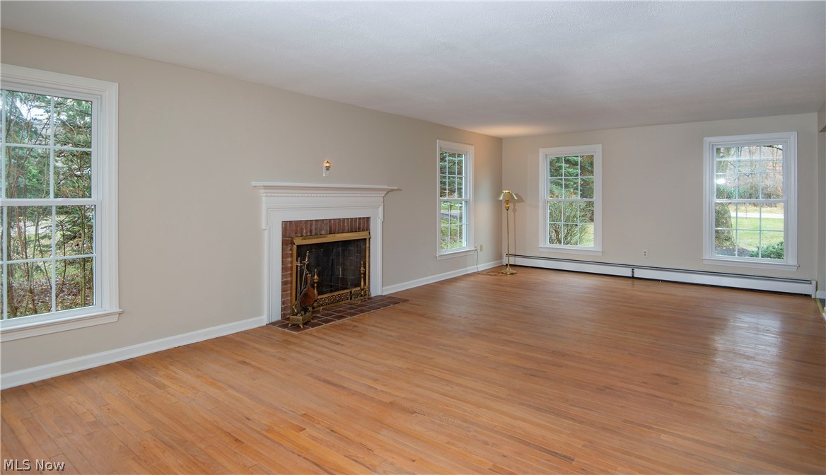 Very large formal living room spans from the front to the back of the house with centrally placed classic brick  wood-burning fireplace, hardwood flooring and fresh paint.