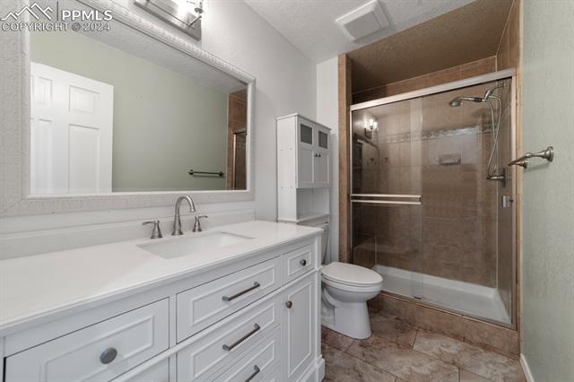 3240 Spaatz Road Monument, CO 80132 - Photo 18 of 45 Guest Bath featuring tile flooring, an enclosed shower, toilet, and large vanity