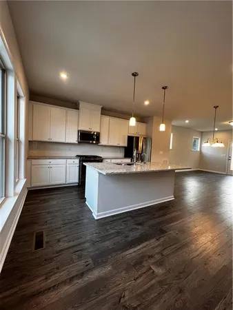 a large kitchen with kitchen island a stove a sink dishwasher and a oven with wooden floor