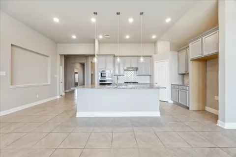 a large white kitchen with a refrigerator a counter top and a sink