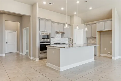 a kitchen with kitchen island granite countertop appliances cabinets and a sink