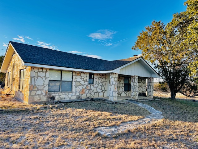 View of front facade featuring stone siding and roof with shingles