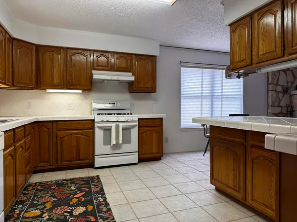 a kitchen with stainless steel appliances granite countertop a stove a sink and a microwave
