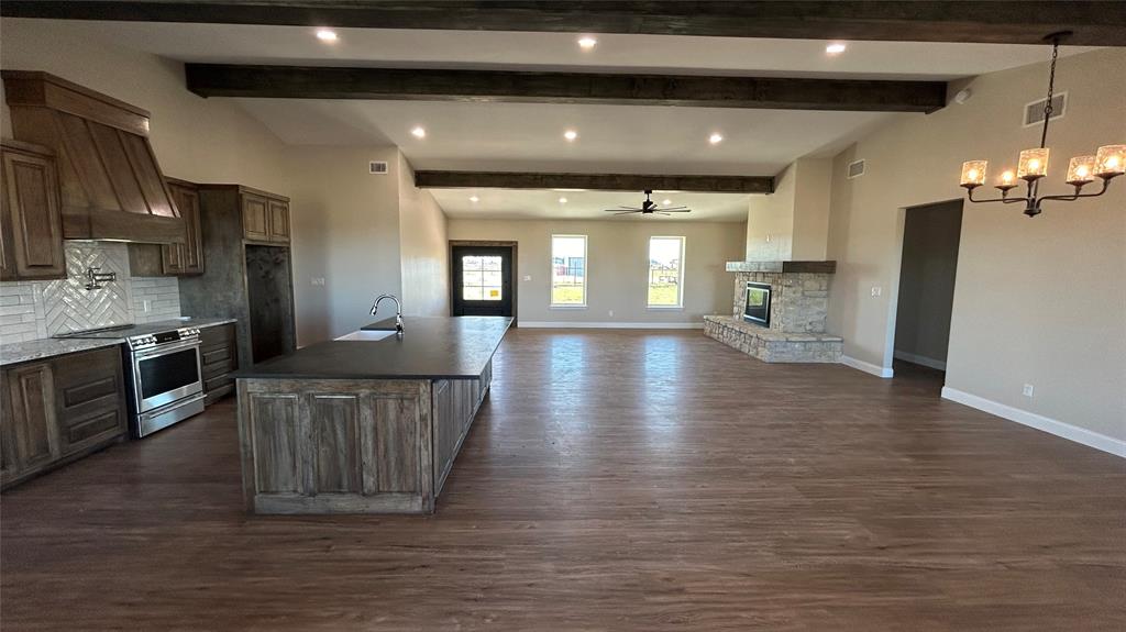 8740 Star Hollow Road Lipan, TX 76462 - Photo 2 of 40 a large room with stainless steel appliances kitchen island granite countertop a large kitchen island a stove a refrigerator white cabinets with wooden floor