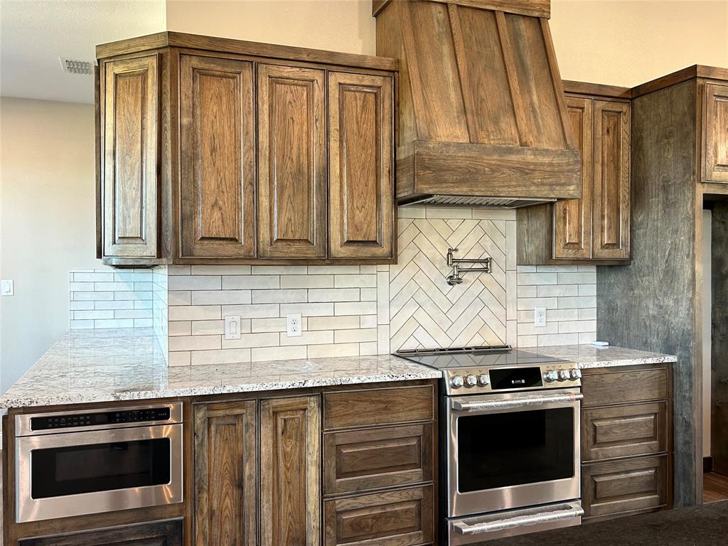 8740 Star Hollow Road Lipan, TX 76462 - Photo 32 of 40 a kitchen with granite countertop a stove and a sink