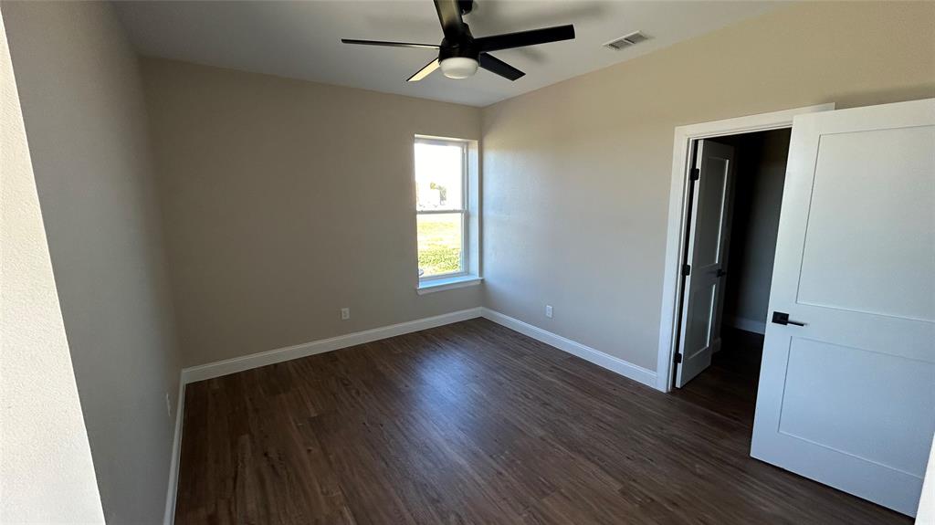 8740 Star Hollow Road Lipan, TX 76462 - Photo 5 of 40 an empty room with wooden floor a ceiling fan and windows