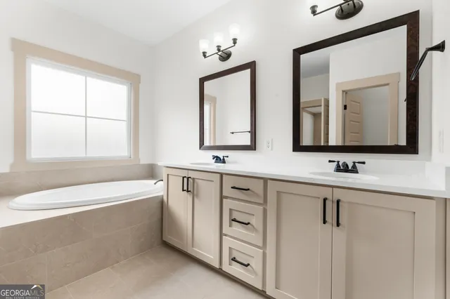 a bathroom with a double vanity sink a mirror and a bathtub