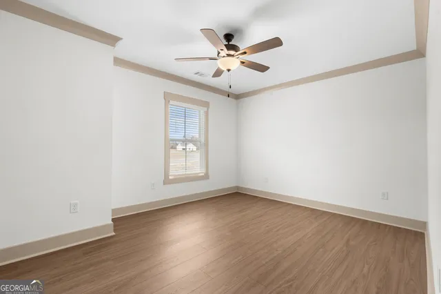 an empty room with wooden floor fan and windows