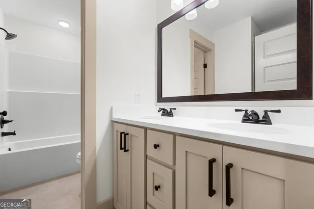 a bathroom with a double vanity sink a mirror and a bathtub
