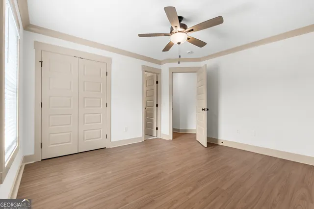 an empty room with wooden floor and ceiling fan