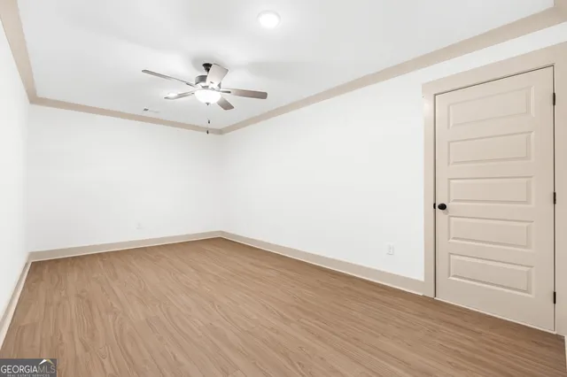 an empty room with a hardwood and ceiling fan