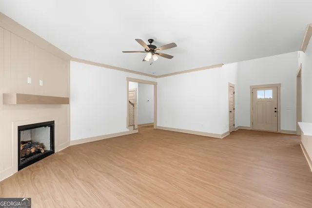 an empty room with chandelier fan and fireplace