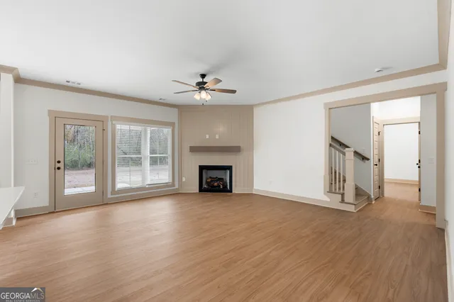a view of an empty room with a window and wooden floor