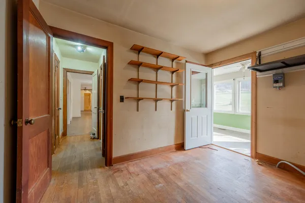 an empty room with a chandelier fan and windows