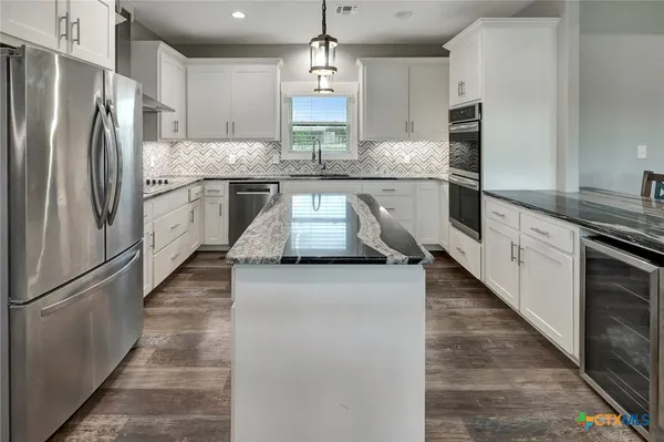 a kitchen with stainless steel appliances granite countertop a sink a stove and a refrigerator