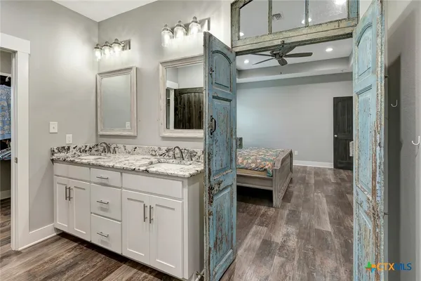 a en suite bathroom with a granite countertop sink and a mirror