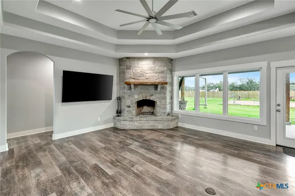 a view of a livingroom with a fireplace a ceiling fan and windows