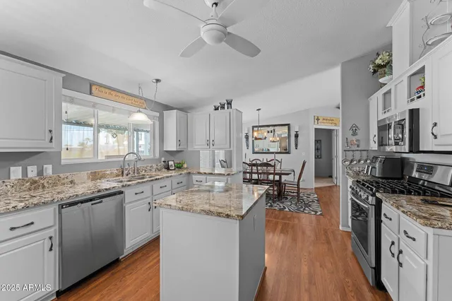 a kitchen with stainless steel appliances granite countertop a lot of counter space and wooden floors