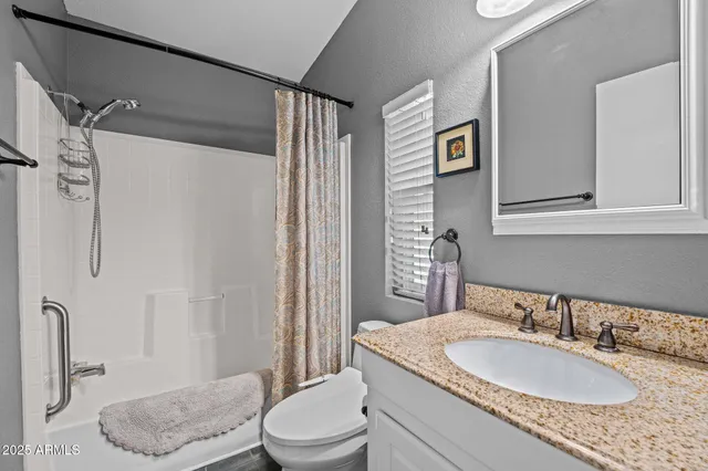 a bathroom with a granite countertop sink toilet a mirror a vanity and shower