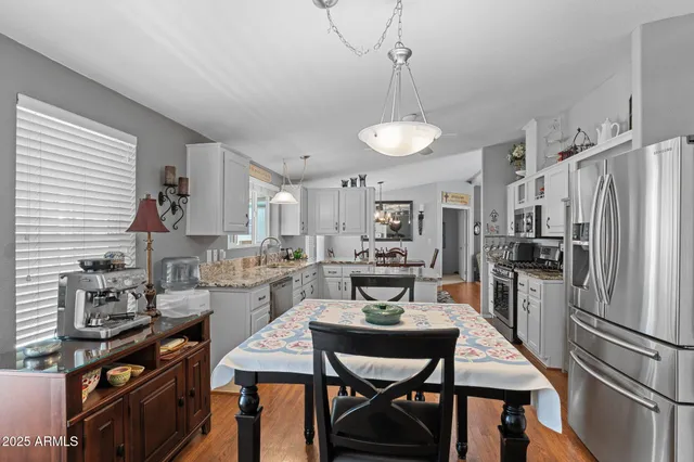 a kitchen with stainless steel appliances a dining table chairs stove and refrigerator