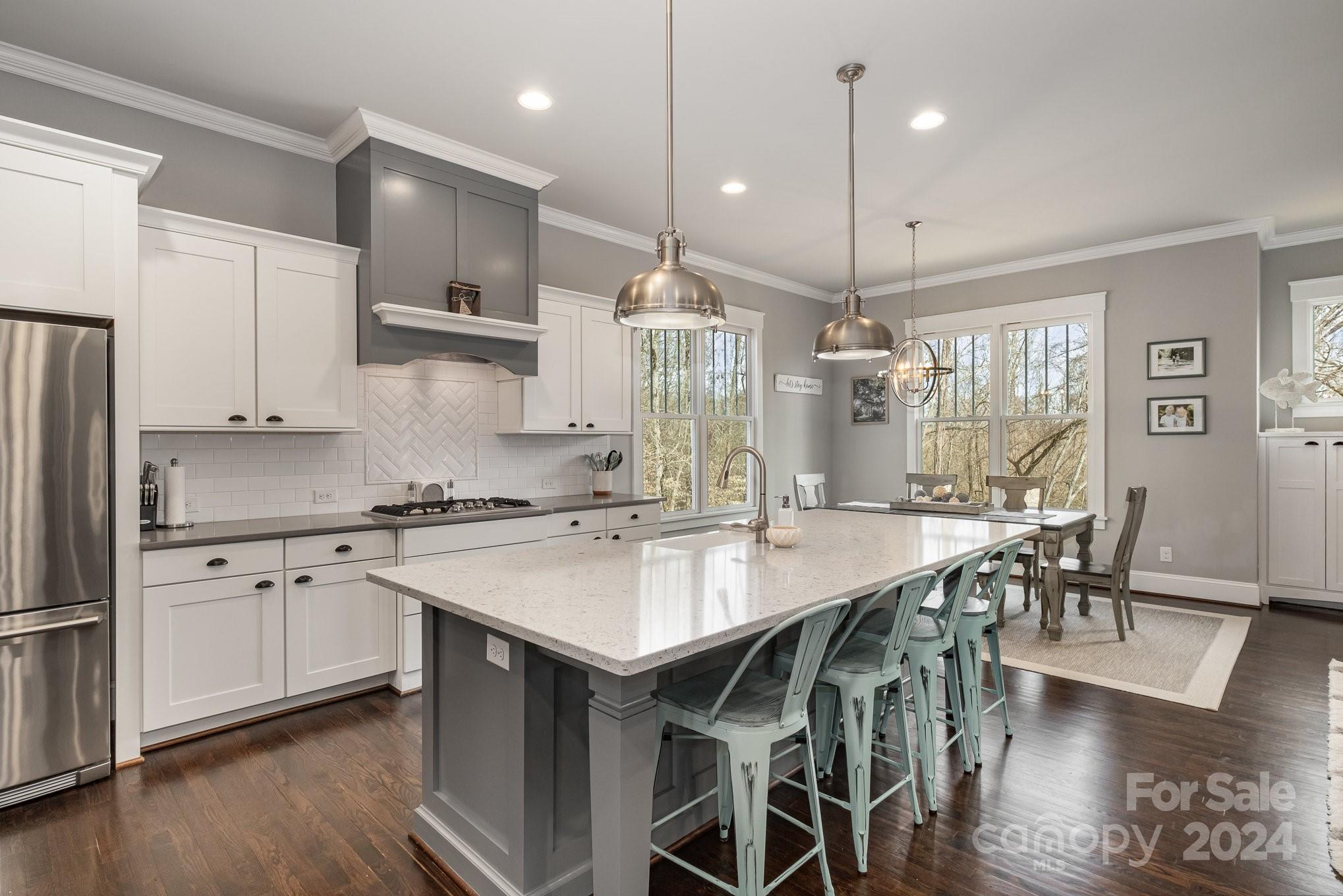 2289 Tatton Hall Road Fort Mill, SC 29715 - Photo 5 of 48 a kitchen with stainless steel appliances granite countertop a stove a refrigerator a kitchen island a dining table and chairs with wooden floor
