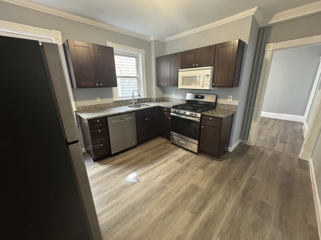 a large kitchen with granite countertop a refrigerator and a stove top oven