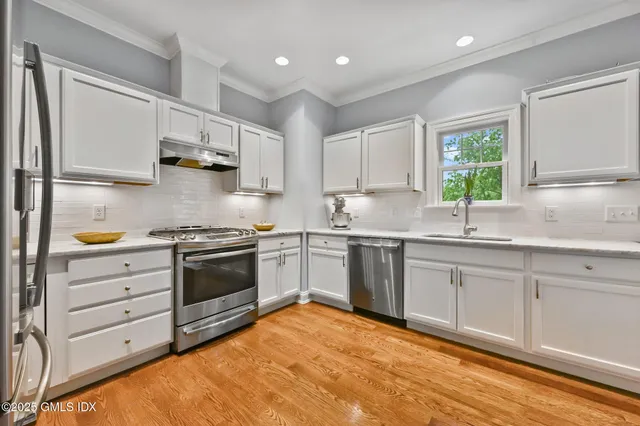 a kitchen with granite countertop a sink stainless steel appliances and cabinets