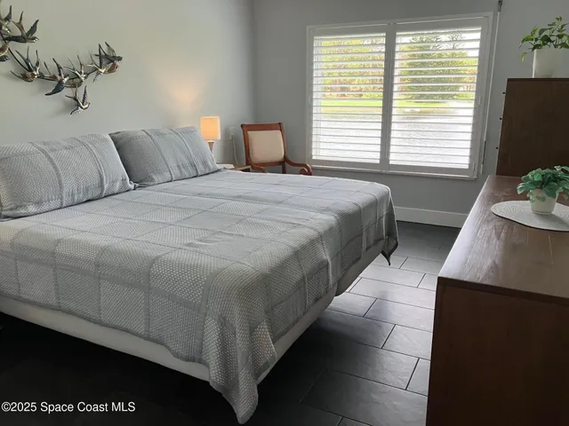 a bedroom with a bed and a flat tv screen on dresser