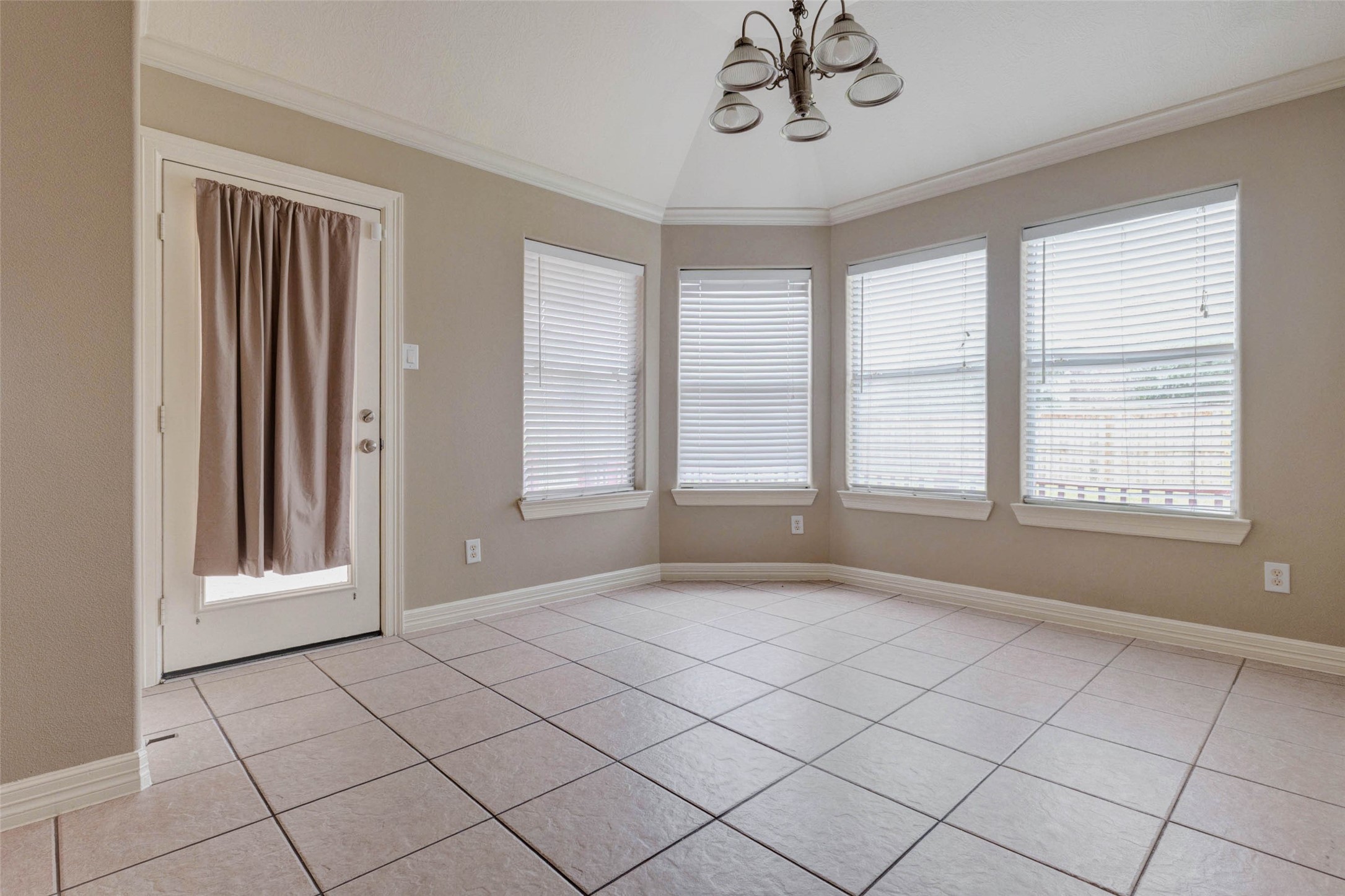 2718 Ridgeglen Lane Houston, TX 77082 - Photo 10 of 26 Bright dining or breakfast area with tile flooring, crown molding, chandelier lighting and multiple windows fitted with blinds. The angled wall of windows brings in natural light and creates an inviting spot for everyday meals, morning coffee or a casual work-from-home setup. A rear door provides convenient access to the outdoor area, while neutral walls and white trim keep the space clean and versatile.