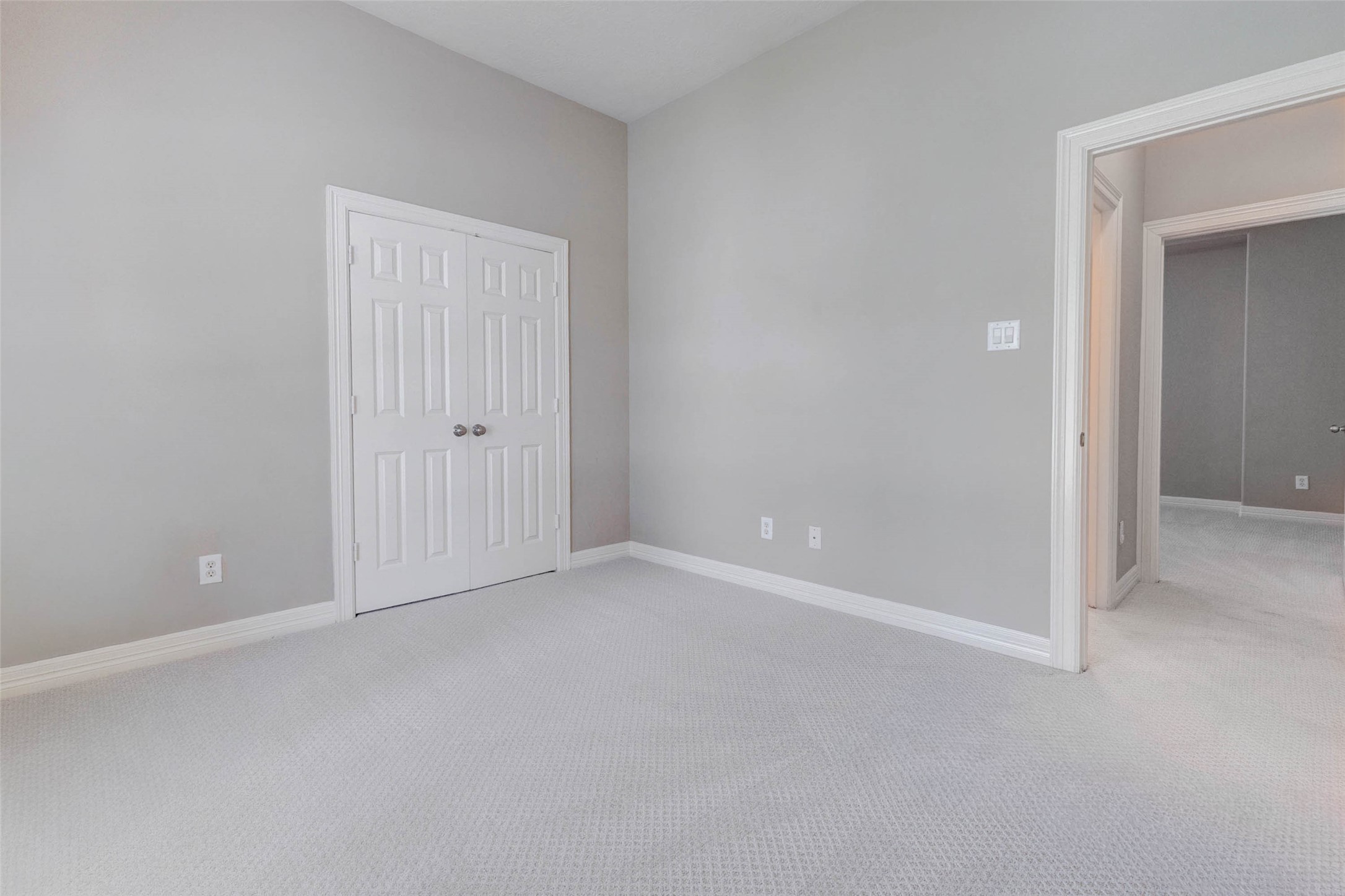 2718 Ridgeglen Lane Houston, TX 77082 - Photo 12 of 26 Alternate bedroom view showing the generous wall space, double closet doors, neutral paint and soft carpet. The tall ceiling adds an open feel, while the doorway connection highlights the easy flow to the hall and nearby rooms. This flexible secondary bedroom offers a simple, functional layout with plenty of room for furniture placement, décor and everyday living.