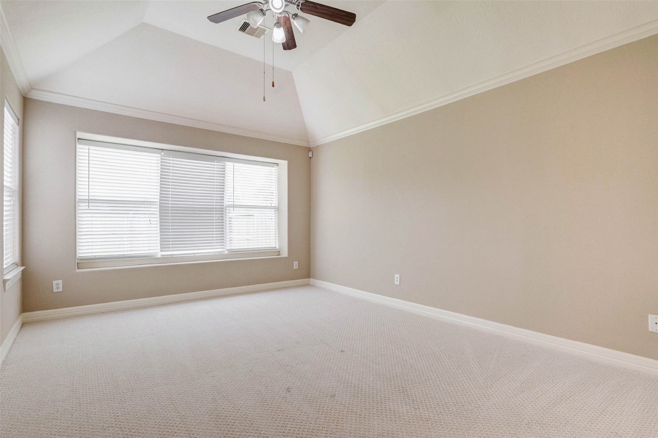 2718 Ridgeglen Lane Houston, TX 77082 - Photo 16 of 26 Large bedroom with vaulted ceiling, crown molding, ceiling fan and a broad window that brings in soft natural light. Neutral walls and light carpet create a calm, airy feel, while the generous floor area allows for multiple furniture arrangements. The elevated ceiling adds dimension and openness, making the room feel spacious, comfortable and ready for a variety of personal styles.