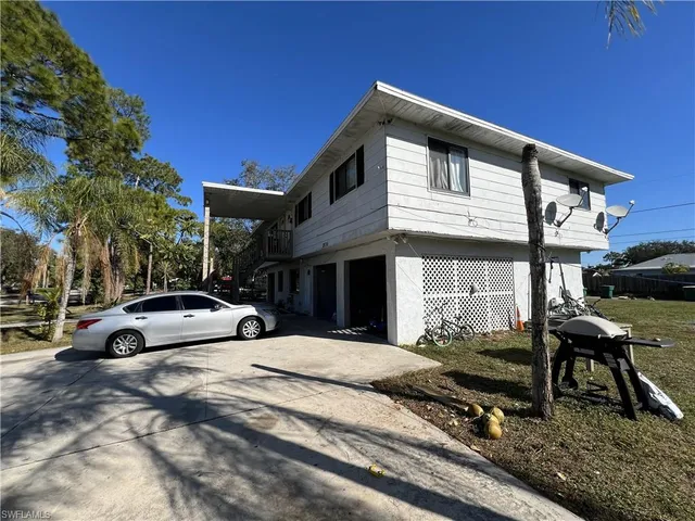 a view of a white house with a big yard and large trees
