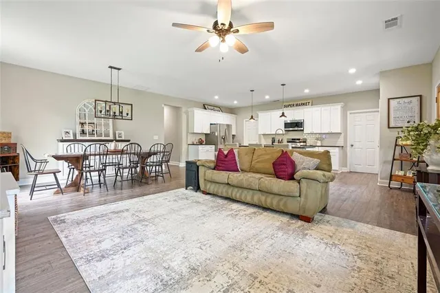 a living room with furniture and a dining table with wooden floor